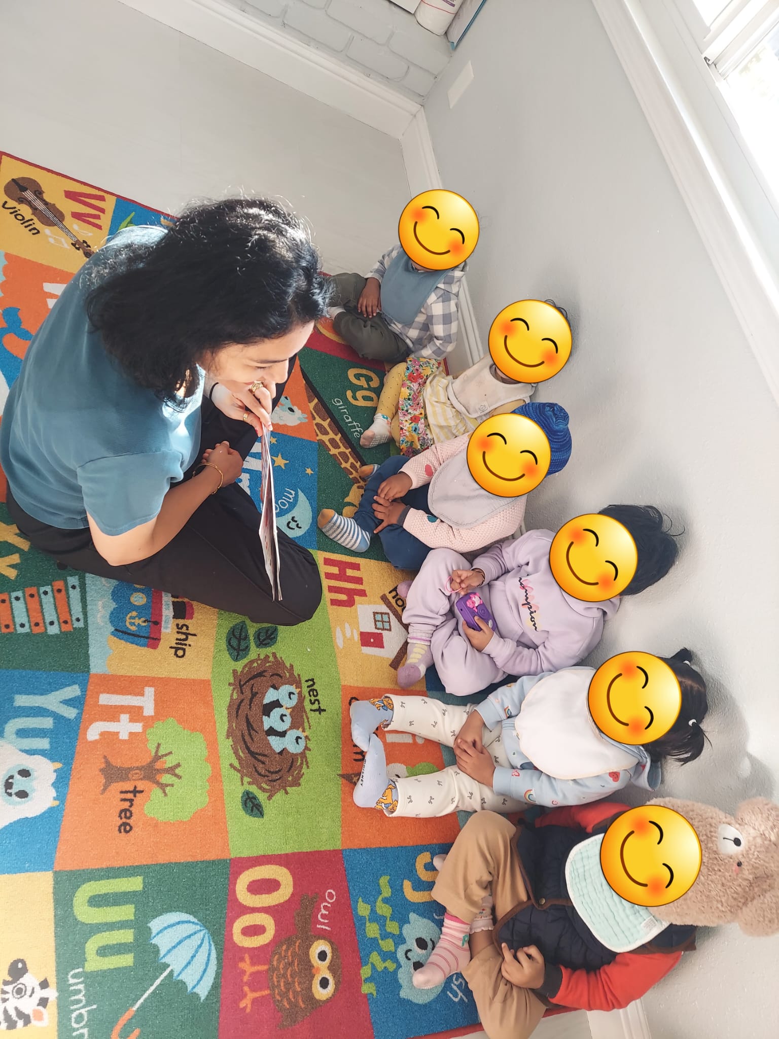 Caregiver reading with children during floor play